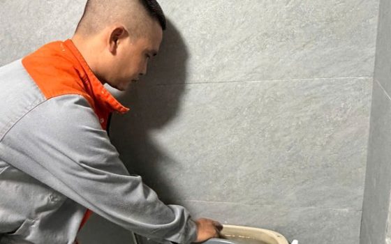 Thợ kiểm tra két nước bồn cầu khi bồn cầu chảy nước