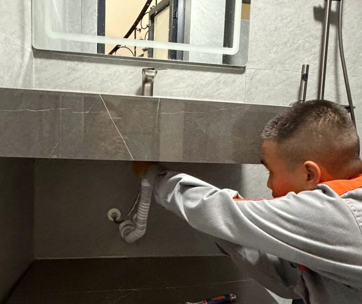 Thợ sửa thiết bị vệ sinh dưới chậu lavabo